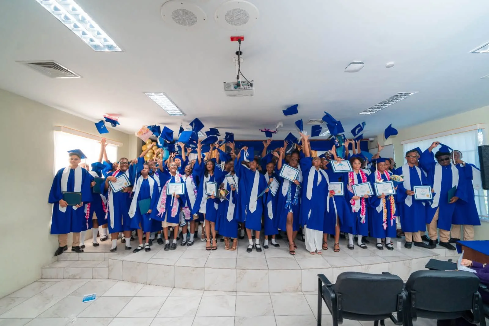 Morgan’s graduates celebrating with certificates and tossing their blue caps
